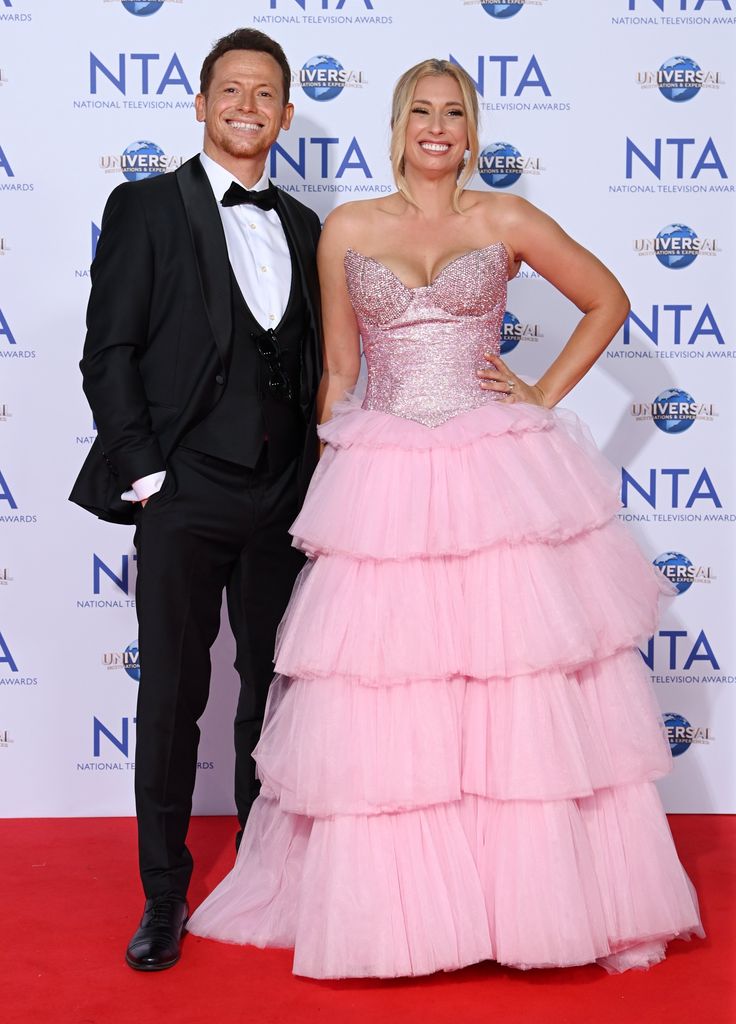 Joe Swash in tuxedo stood next to Stacey Solomon in pink dress