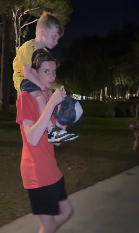 Teenage boy carrying young boy on his shoulders