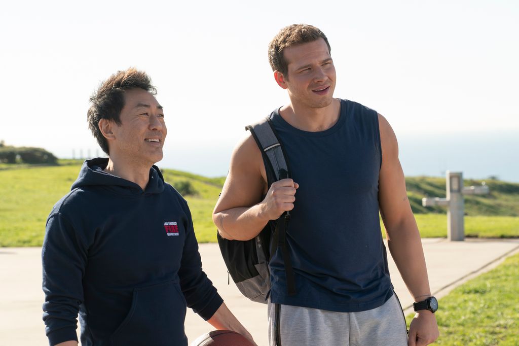 Kenneth Choi as Chim and Oliver Stark as Buck stand on an outdoor basketball court