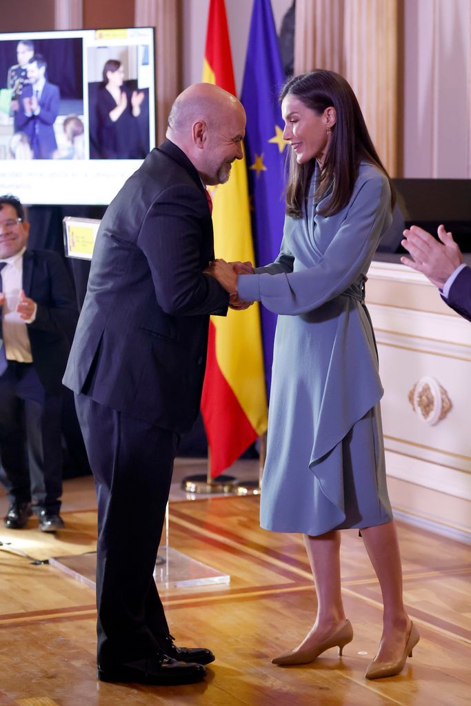 Queen Letizia shaking man's hand in a wrap dress