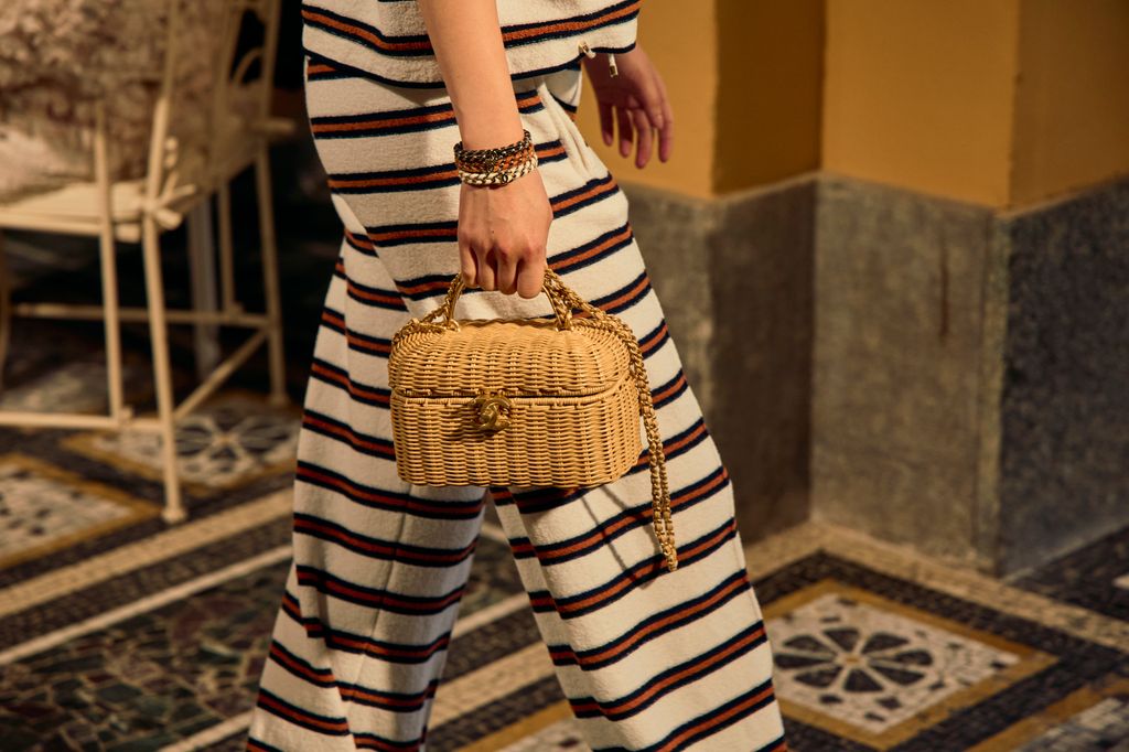 woman holding straw chanel bag