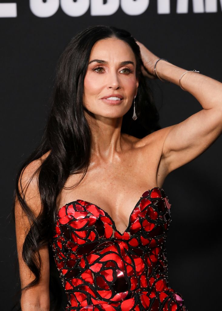 Demi Moore running her hand through her hair in a strapless red dress