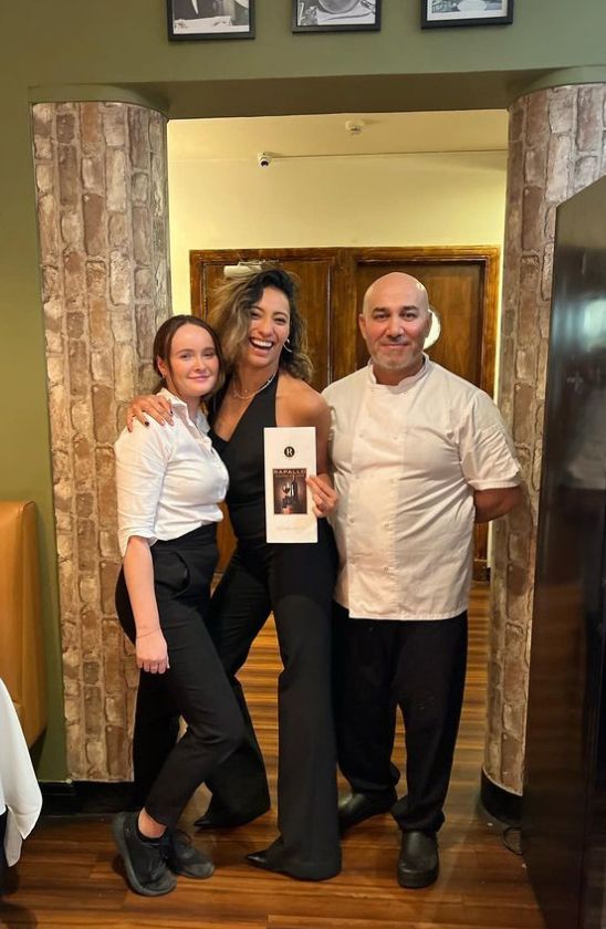Karen Hauer in a jumpsuit with two workers at a restaurant