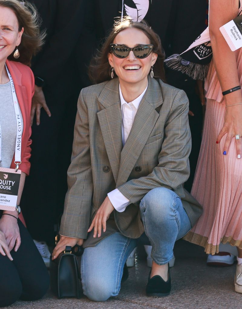 Natalie crouched down smiling for a photo, her hands are ringless