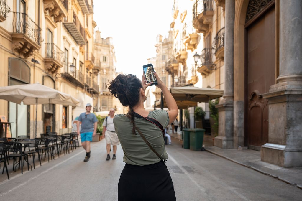 Rear view of tourist taking pictures in the old town of Palermo, Sicily, Italy