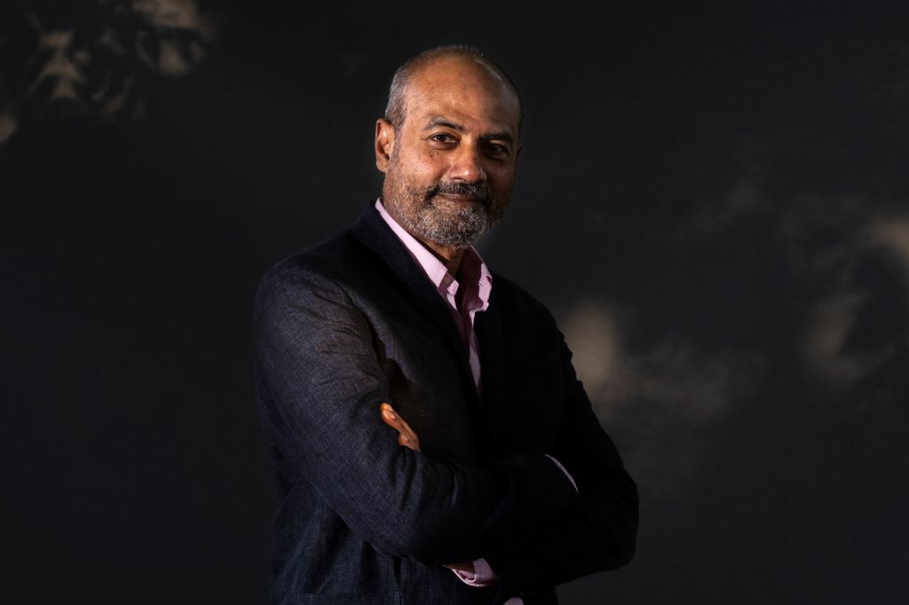 BBC's George Alagiah smiles and crosses his arms
