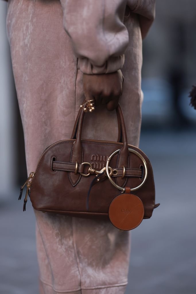 Fashion Week Guest seen wearing a creme brown wool coat, a Miu Miu brown leather bag 