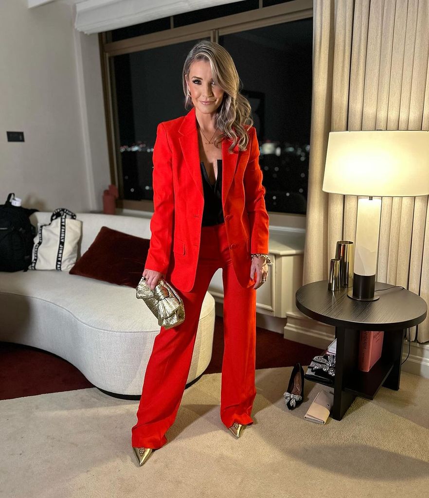Helen Skelton in a red suit holding a gold bag