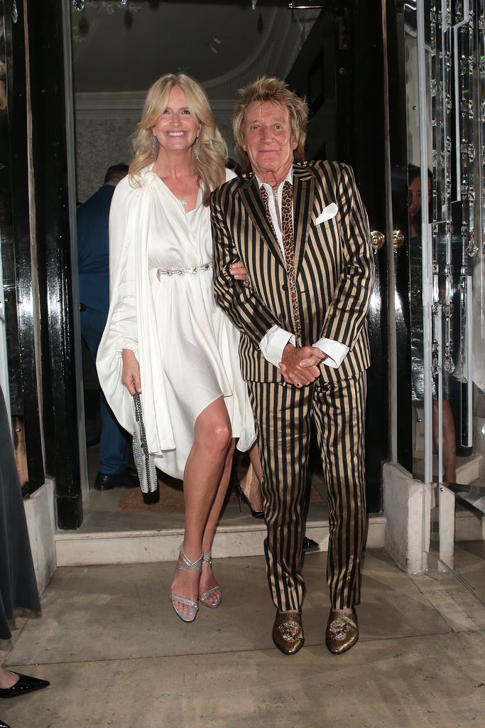 Penny Lancaster in white and Rod Stewart in stripes posing at Annabels