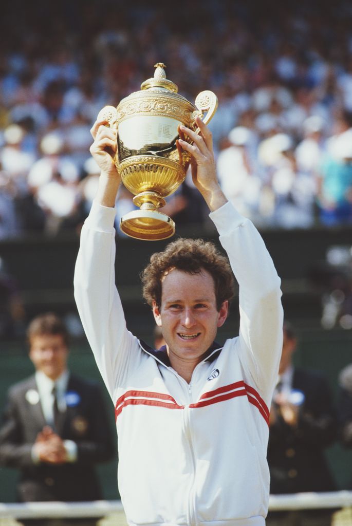 John McEnroe in 80s holding tennis trophy