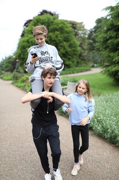 A young boy on his older brother's shoulders as their sister walks with them