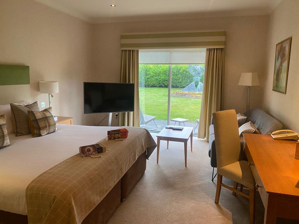 Hotel room with bed, television, table and French windows