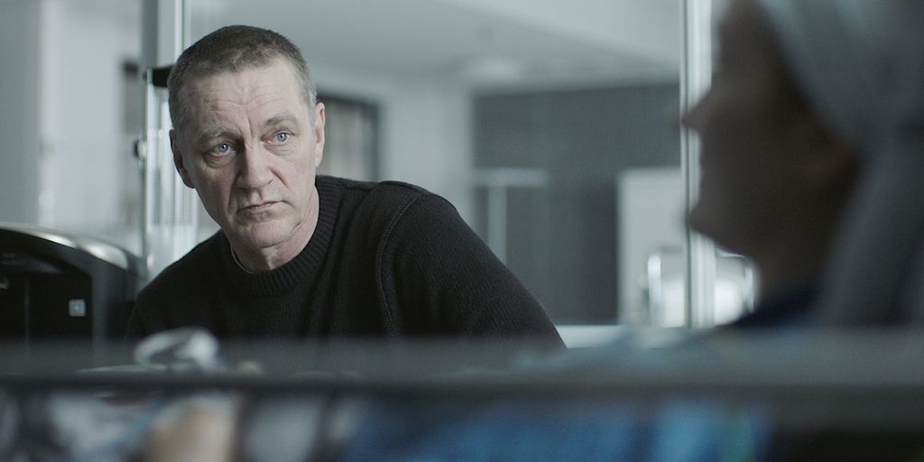 man sitting next to woman in hospital bed 