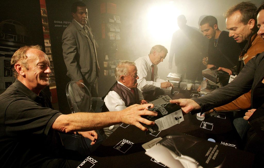 Fans of Star Wars trilogy movies ask actors Kenneth Colley (L) alias Amiral Piettto, Kerny Baker (C) alias R2-D2 and Jeremy Bulloch alias Boba Fett to sign autographs on their DVD box during the first sale at a famous store of Les Champs Elysees in Paris, ear