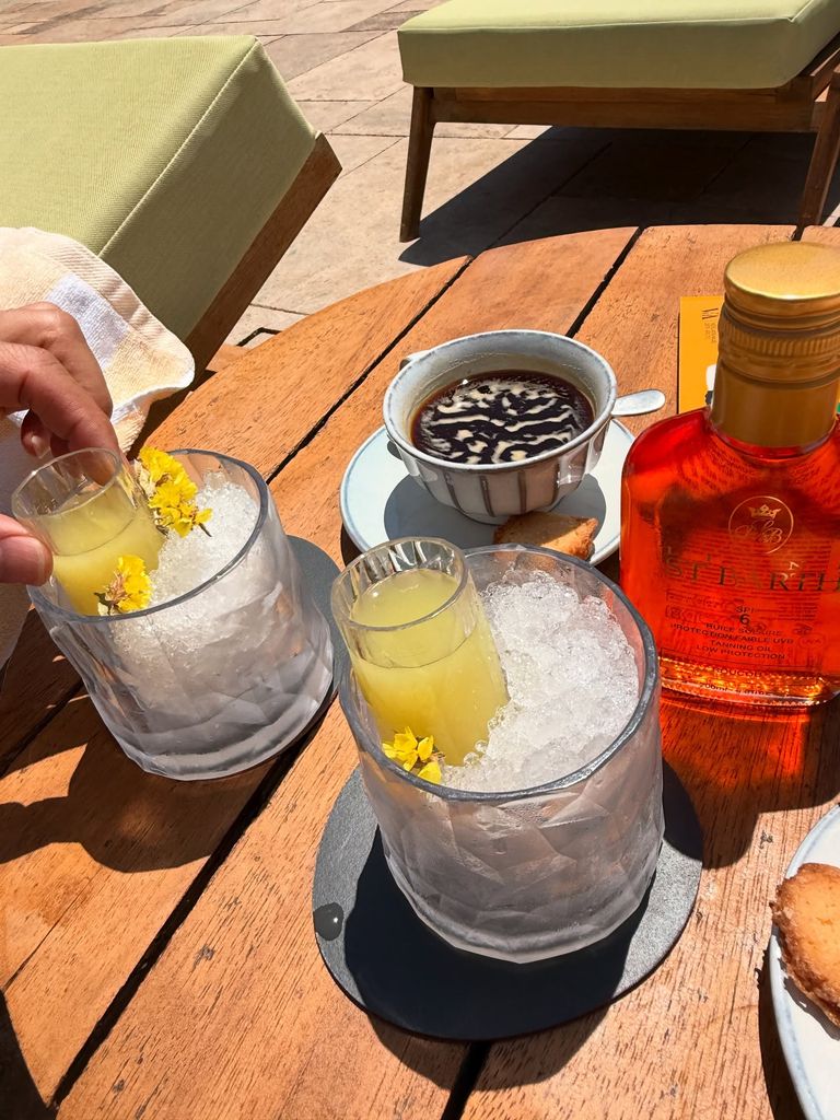 A shot of drinks on a wooden table, from above, including two cocktails and one coffee