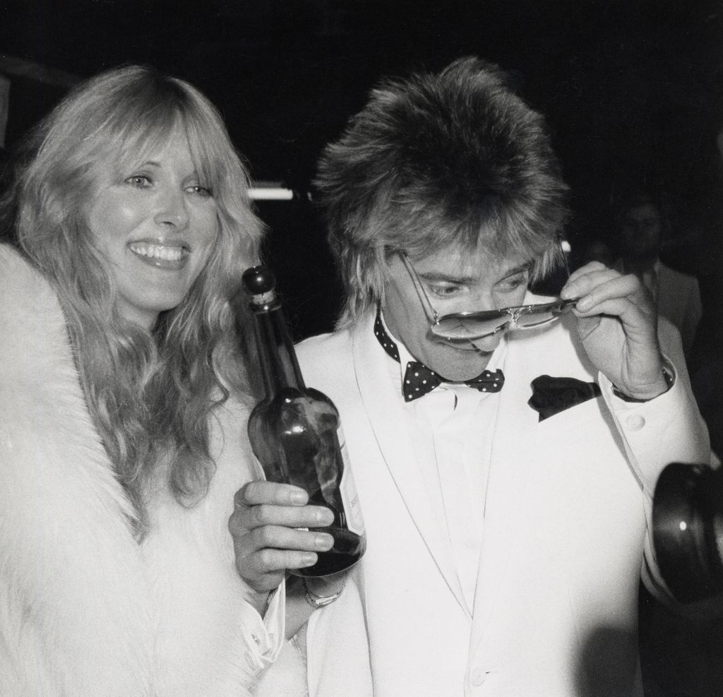 Rod Stewart holding a wine bottle with Alana Stewart