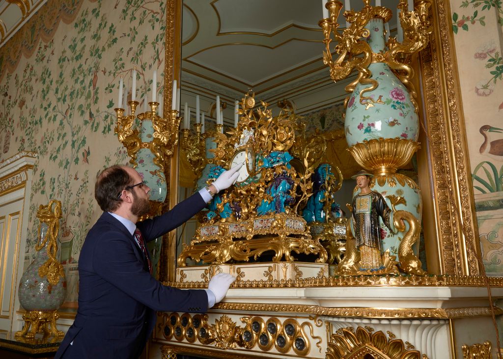 A Horological Conservator adjusts a late-18th-century mantel clock, known as the Kylin clock in the Yellow Drawing Room in the East Wing of Buckingham Palace