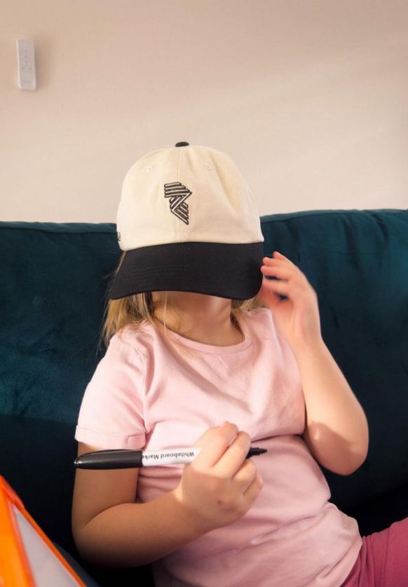 A young girl covering her face with a white cap