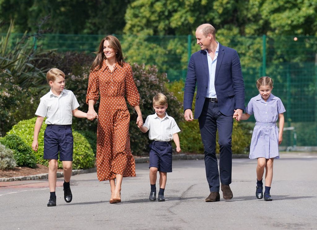 Prince George, Kate Middleton, Prince Louis, Prince William and Princess Charlotte walking towards a school