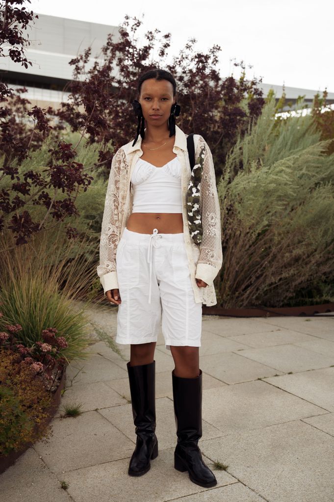 Fia Hamelijnck wears hite shorts, long black boots, white top, sheer shirt and green black and white camouflage bag outside the Marimekko show during day four of the Copenhagen Fashion Week (CPHFW) SS25 on August 08, 2024 in Copenhagen, Denmark. (Photo by Raimonda Kulikauskiene/Getty Images)