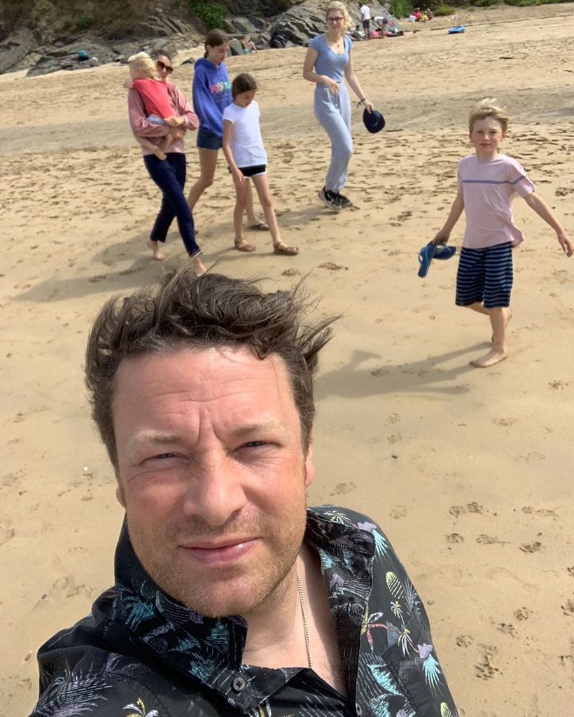 Jamie Oliver posing on beach with wife Jools and his five kids