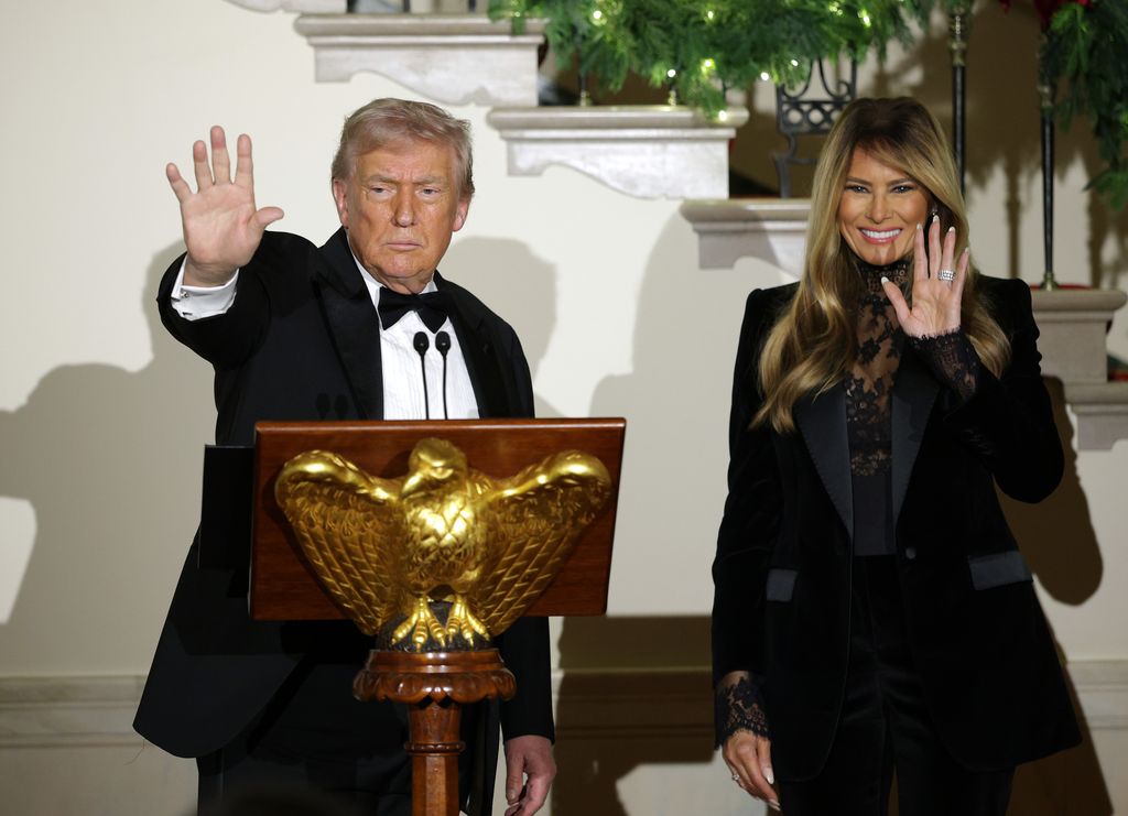President Donald Trump in tuxedo  and First Lady Melania Trump in lace blouse wave to attendees during the Congressional Ball at the Grand Foyer of the White House 