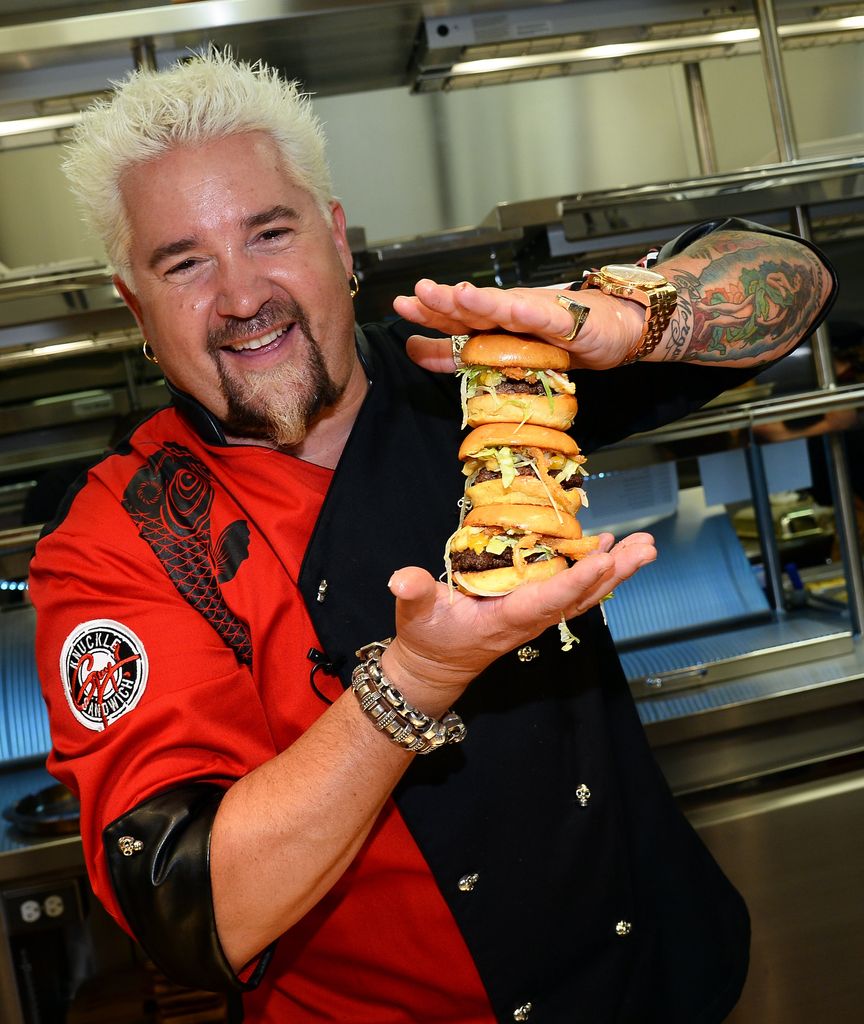 Chef and television personality Guy Fieri holds hamburgers in the kitchen during a welcome event in 2014