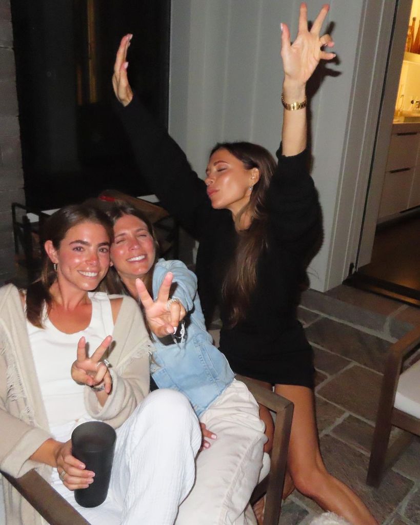 Victoria Beckham in black mini dress with tanned legs posing with friends