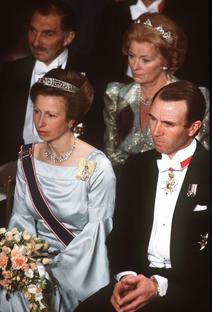 Princess Anne in a blue satin dress and tiara sitting next to her first husband Mark Phillips