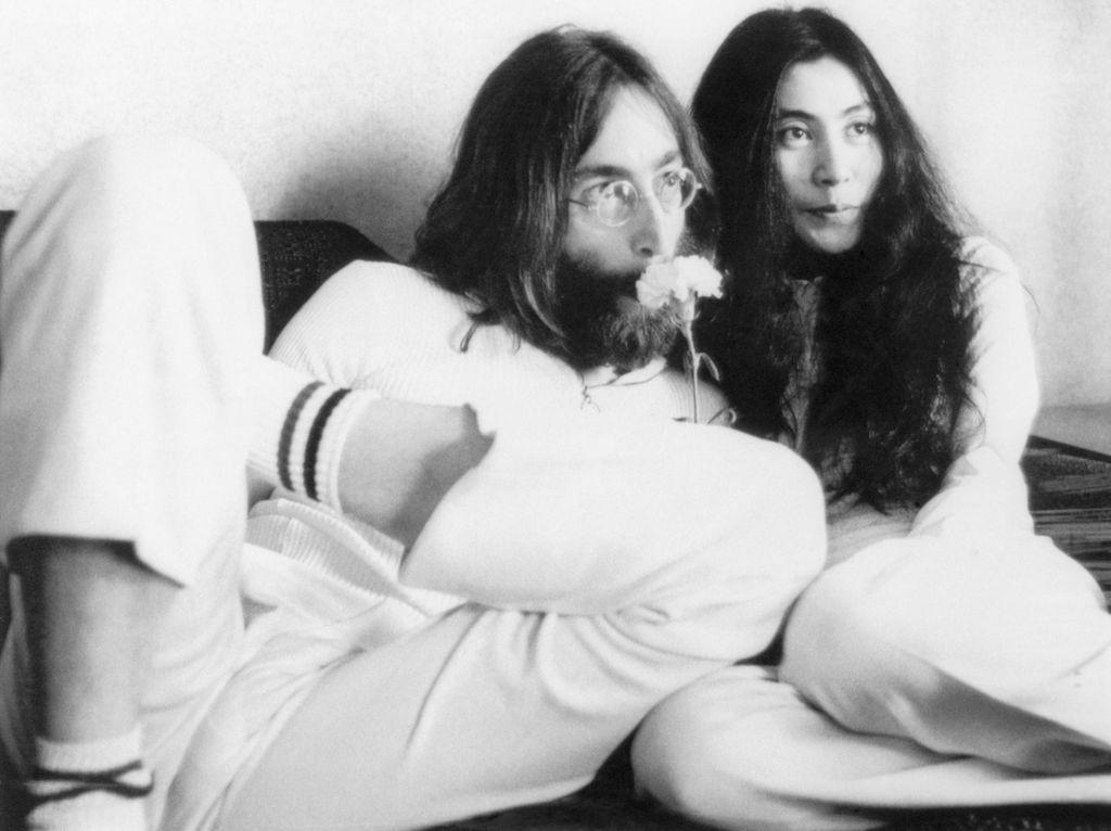 John Lennon s'appuie contre sa femme Yoko Ono au lit et tient une fleur sur son nez.