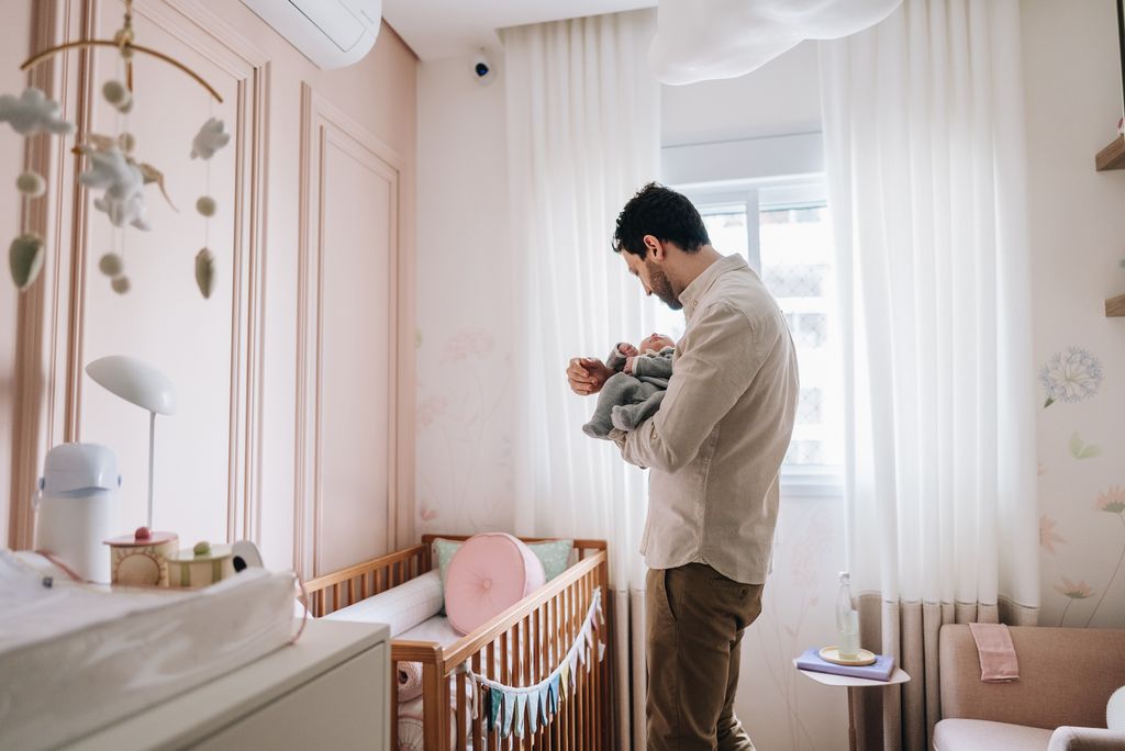 man with tiny baby in pink nursery