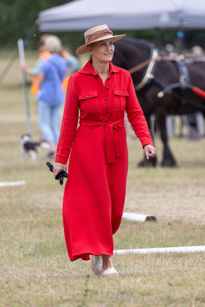 Sophie, Sophie Duchess of Edinburgh walking through field in red dress and boater
