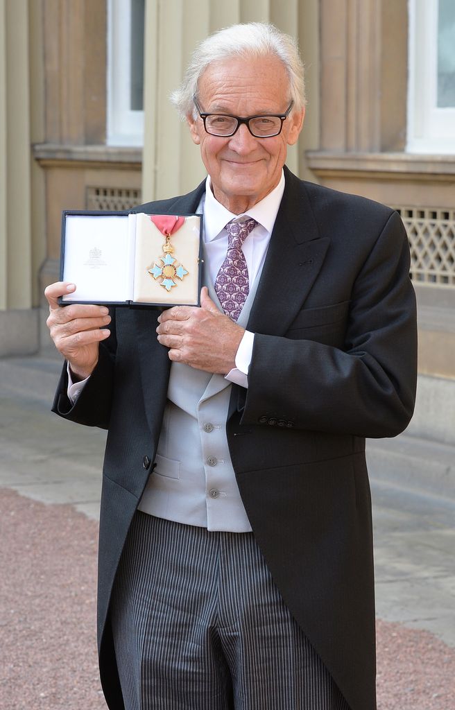 Dr Iain Douglas-Hamilton smiling and holding the Commander of the Order of the British Empire (CBE) medal