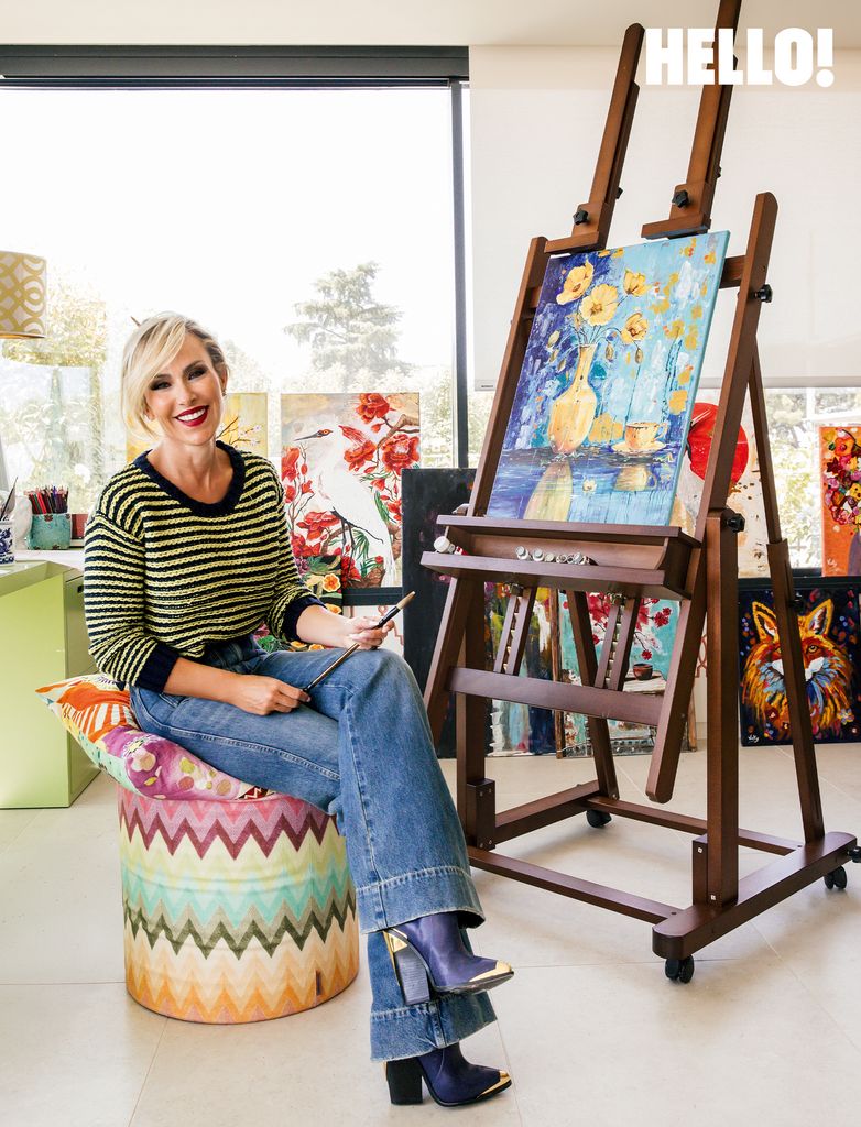 Victoria sat holding a painbrush in her studio inside her three-storey, contemporary-style house