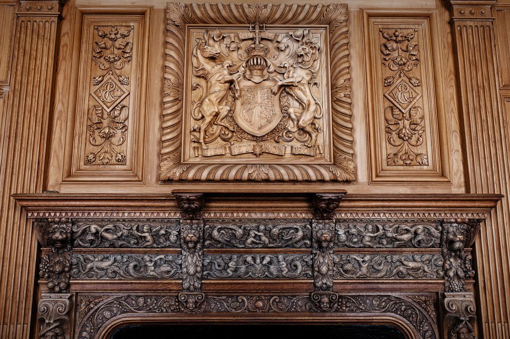 An oak fireplace with a Coat of Arms carved into it