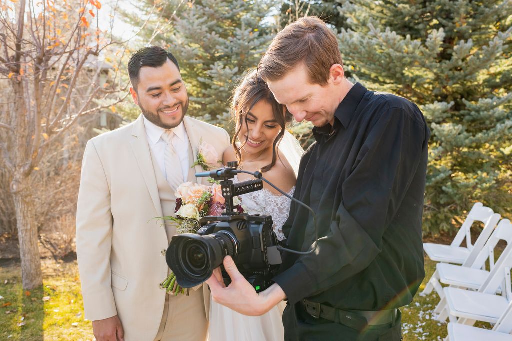 Bride and groom working with camera operator at outdoor wedding