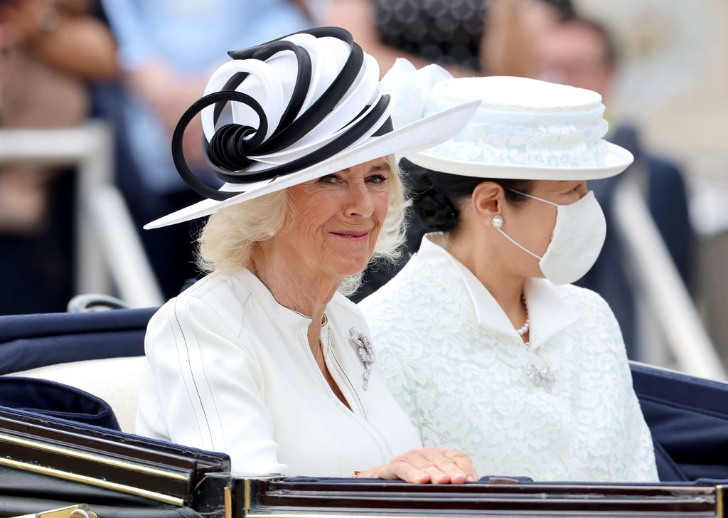 Queen Camilla and Empress Masako of Japan smile as they travel in a carriage procession along The Mall to Buckingham Palace after the ceremonial welcome