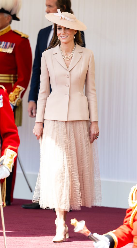Kate in a blush pink skirt, blazer and hat