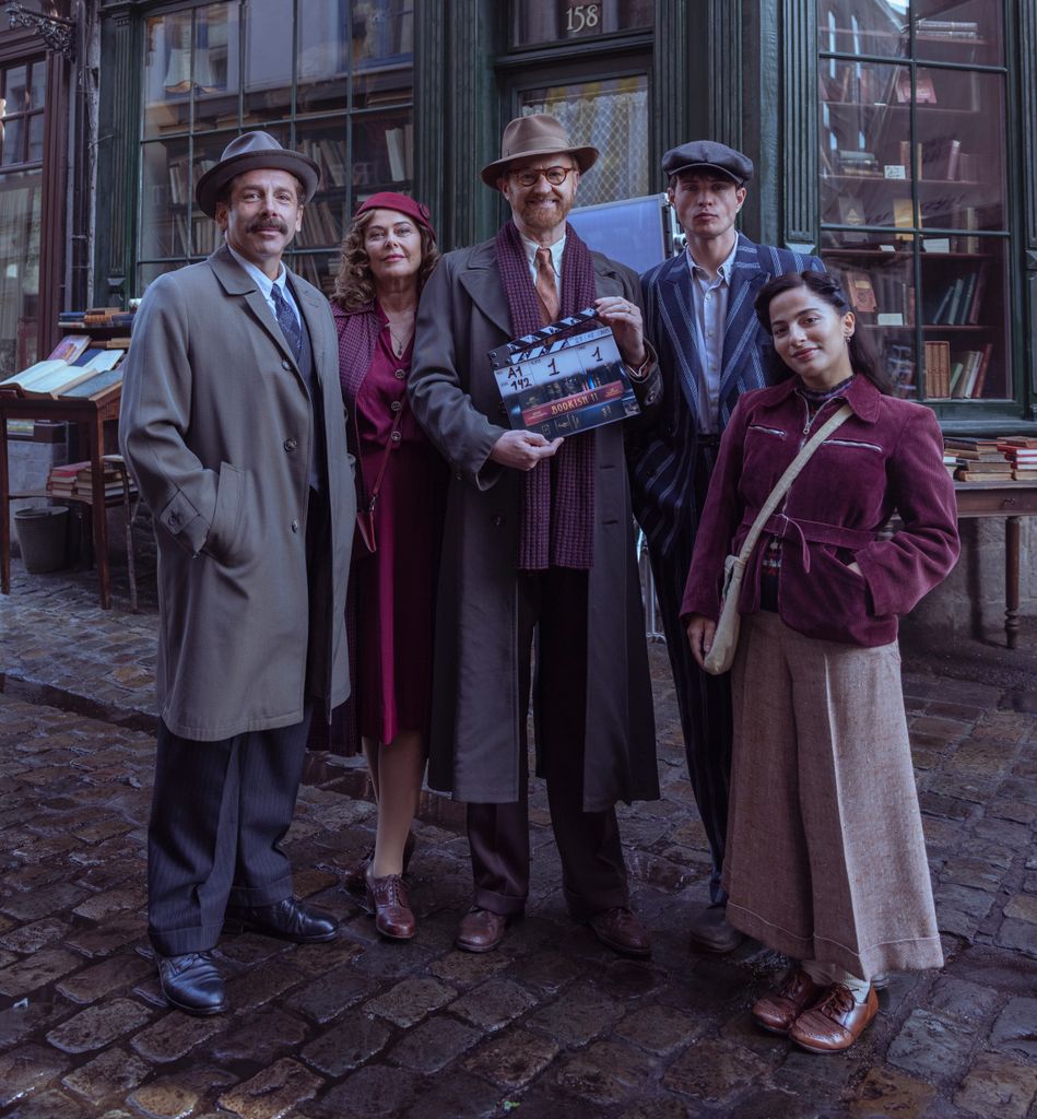 group of people standing in cobbled street holding clapperboard