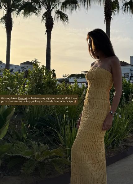 Michelle Keegan standing between palm trees in a yellow dress