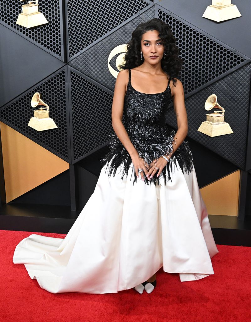 Olivia Dean porte une robe avec une jupe ample blanche et un haut noir à sequins, avec bord frangé en sequins