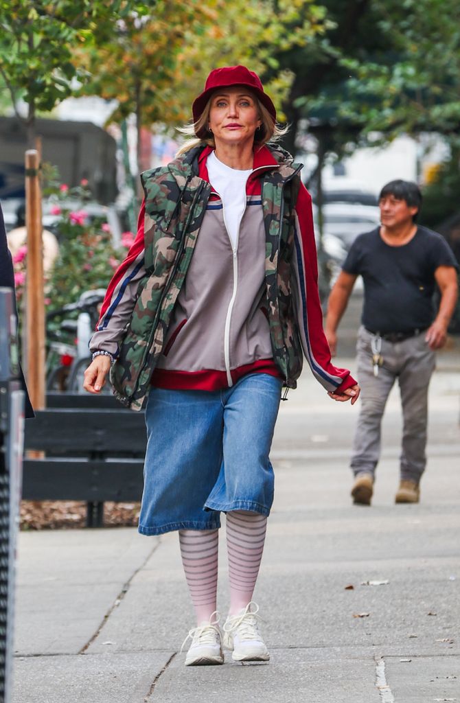 Cameron filming scenes wearing a bucket hat, shorts, striped tights, a parka and mismatched vest