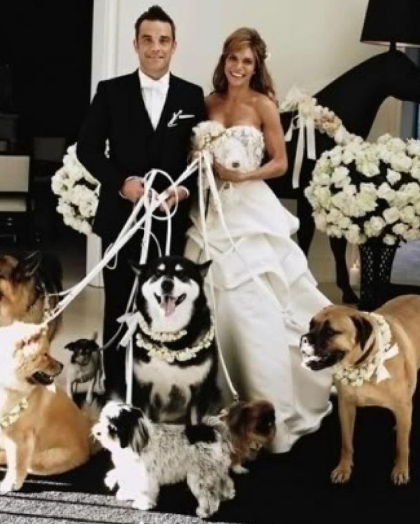 Robbie and Ayda Williams holding dog leads on their wedding day