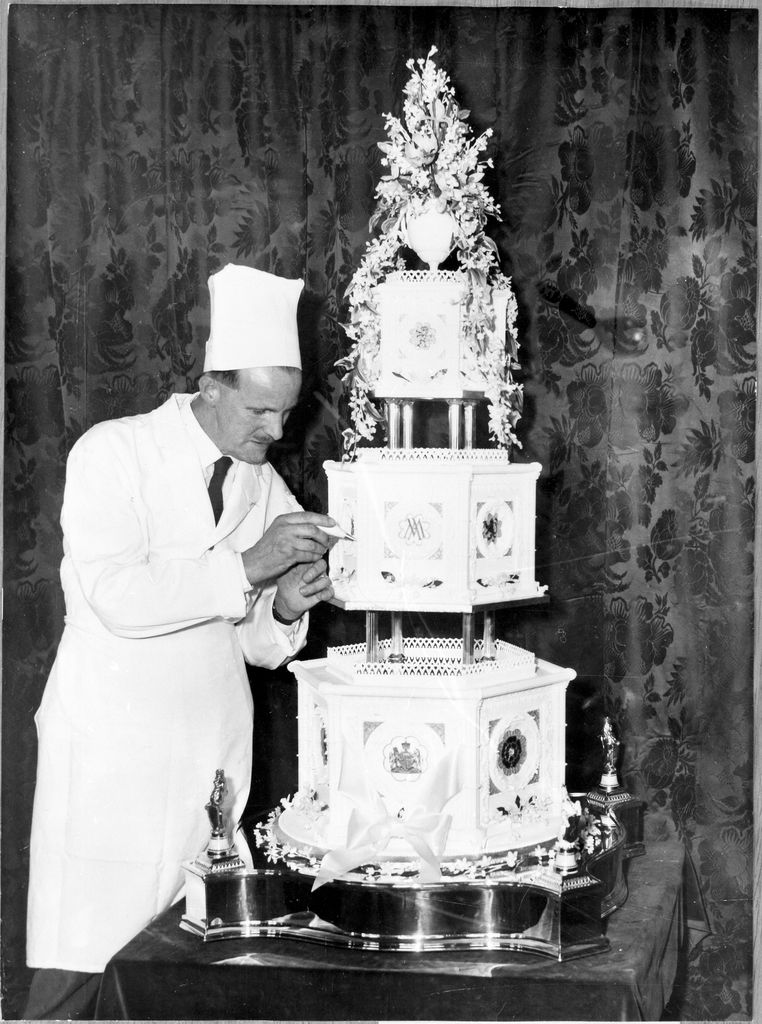 man icing tall wedding cake