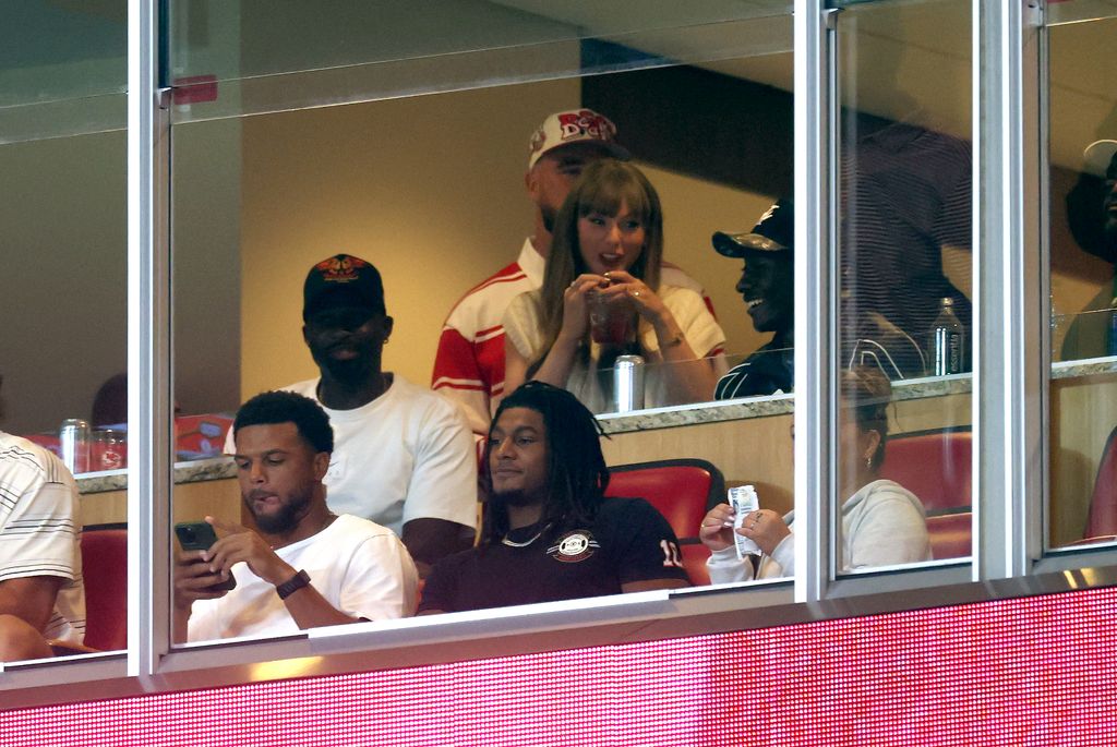 taylor swift in white top and travis kelce in red stripe shirt at  arrowhead stadium