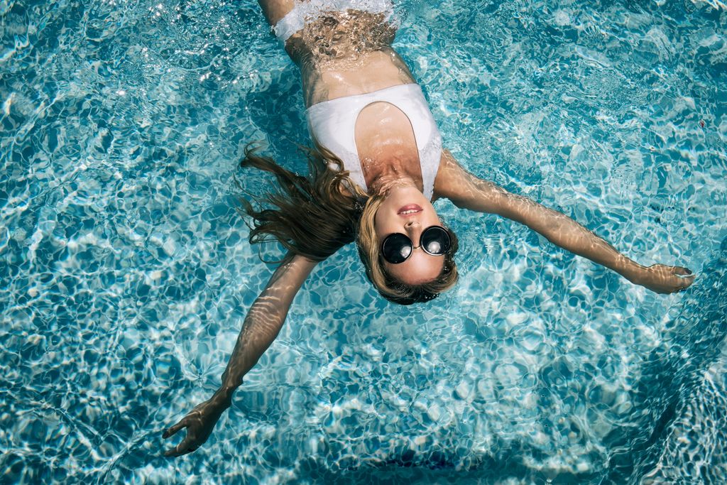Young woman with sunglasses floating in pool