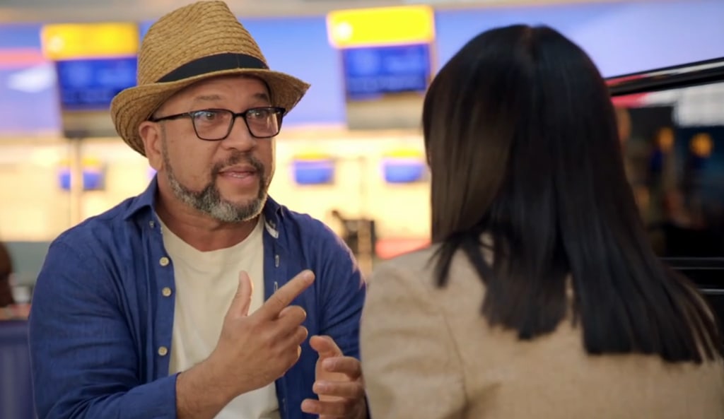 man in hat talking to woman in airport