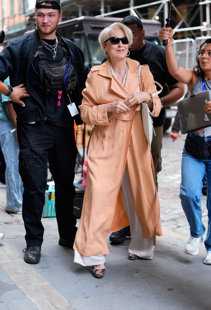 Meryl Streep wearing a peach trench coat on the set of Devil Wears Prada starring as Miranda Priestly
