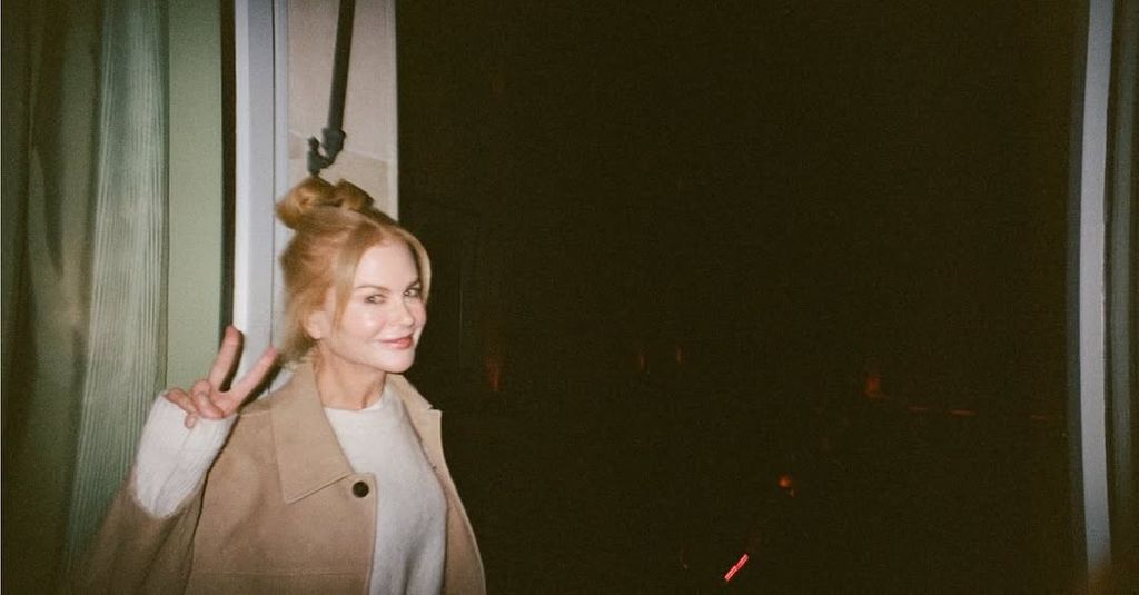 Nicole Kidman in beige trench holding up peace sign
