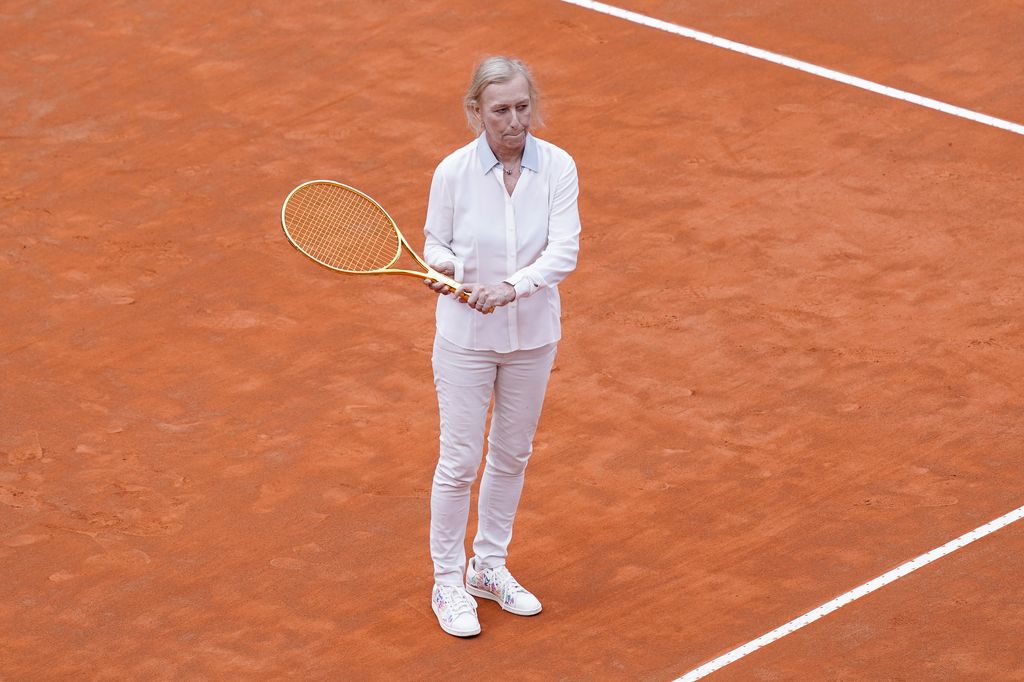 Martina Navratilova standing on her own on a clay court holding a tennis racquet